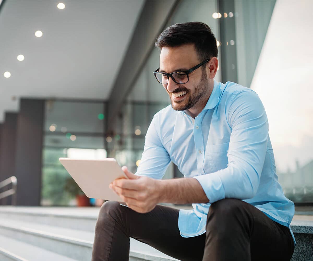 Mann sitzt mit Tablet auf Stiege